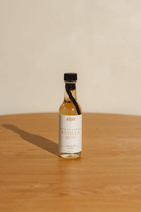 bottle of Sips Madagascar vanilla bean syrup on a wooden surface with a beige background